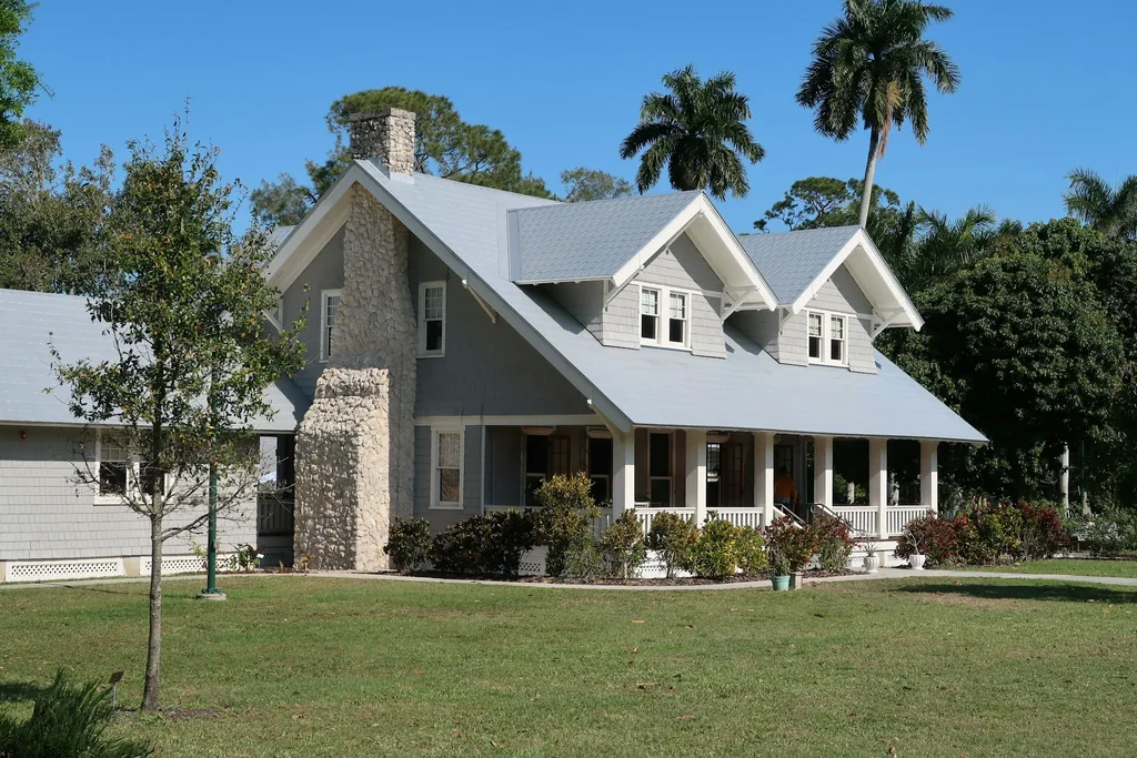 Restored craftsman home with gray siding, metal roof and stone chimney